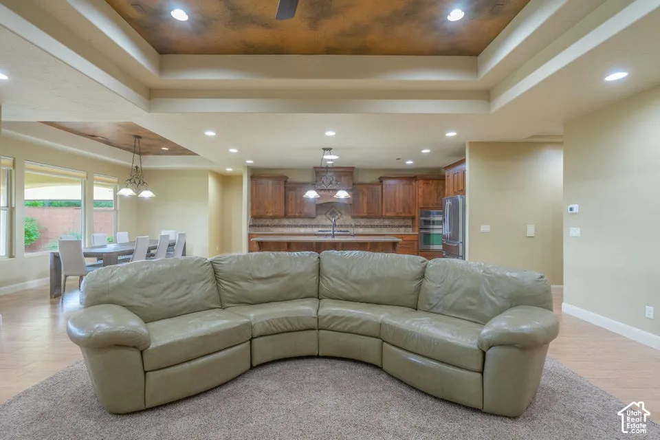 Tray ceilings with recessed lighting, wood-finish flooring, and built-in cabinetry featuring a stone tile backsplash