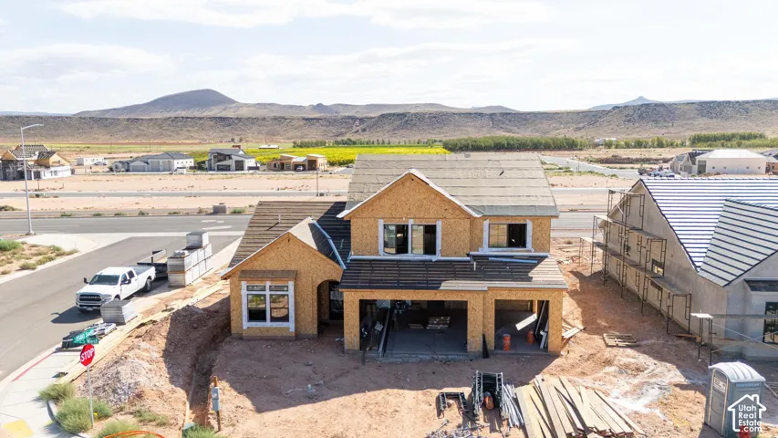 Two-story residence under construction featuring wood-sheathing exterior, multi-gabled roofline, asphalt shingle roofing, and mountain backdrop