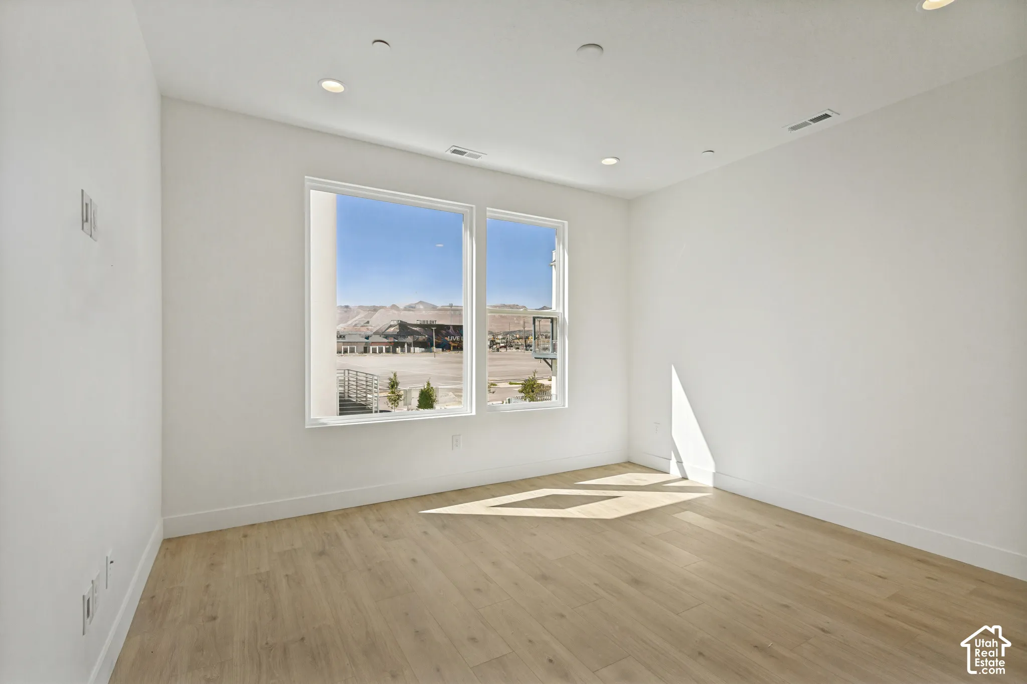 Neutral interior space featuring wood-finish flooring, recessed lighting, and large windows showcasing mountain scenery