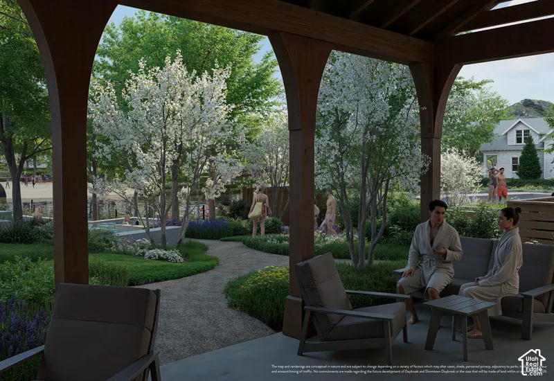 Covered patio featuring arched wood-grain support beams and concrete flooring, overlooking a landscaped garden with gravel pathways, flowering trees, and integrated water features