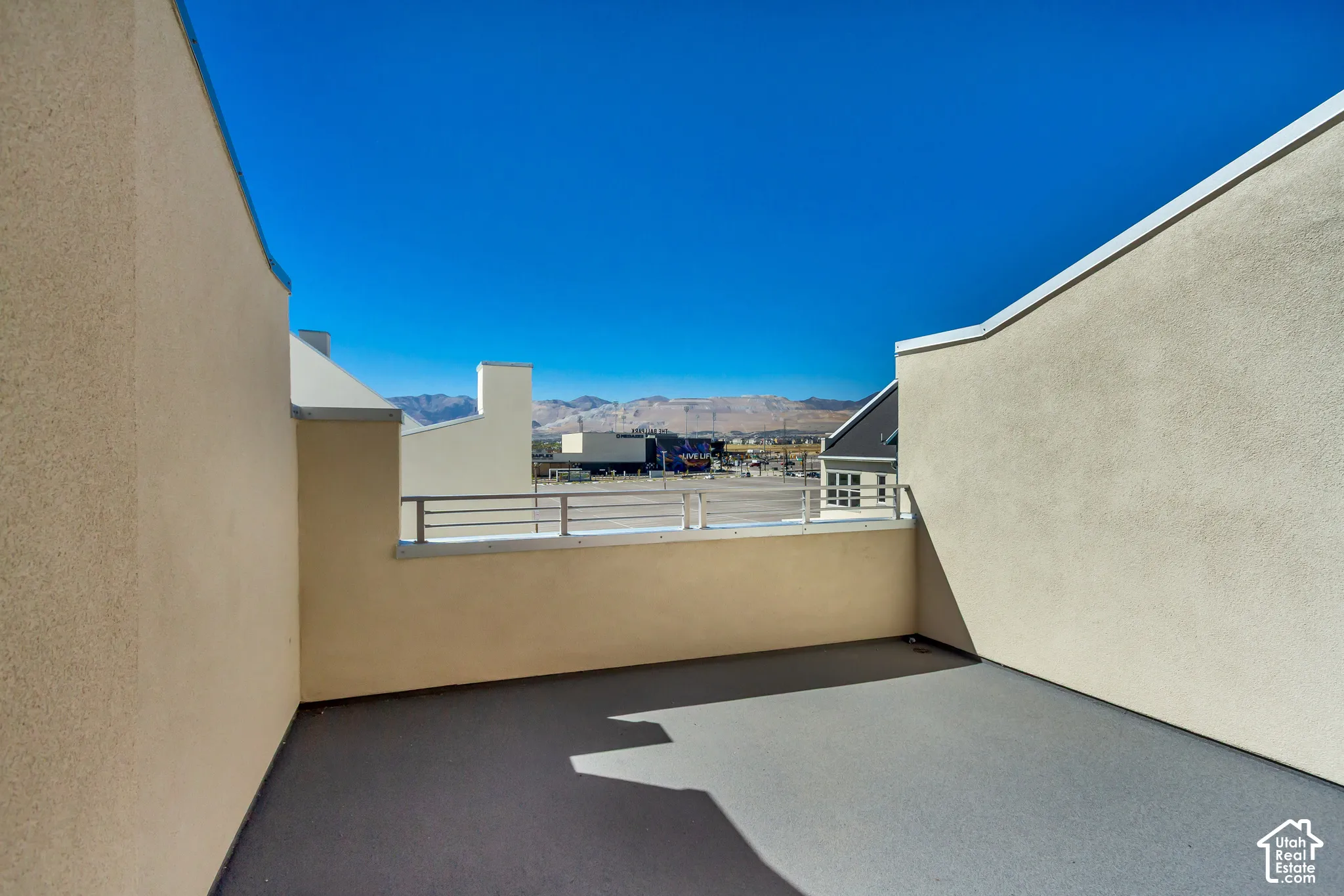 Rooftop deck featuring stucco walls, a horizontal metal railing, and mountain backdrop