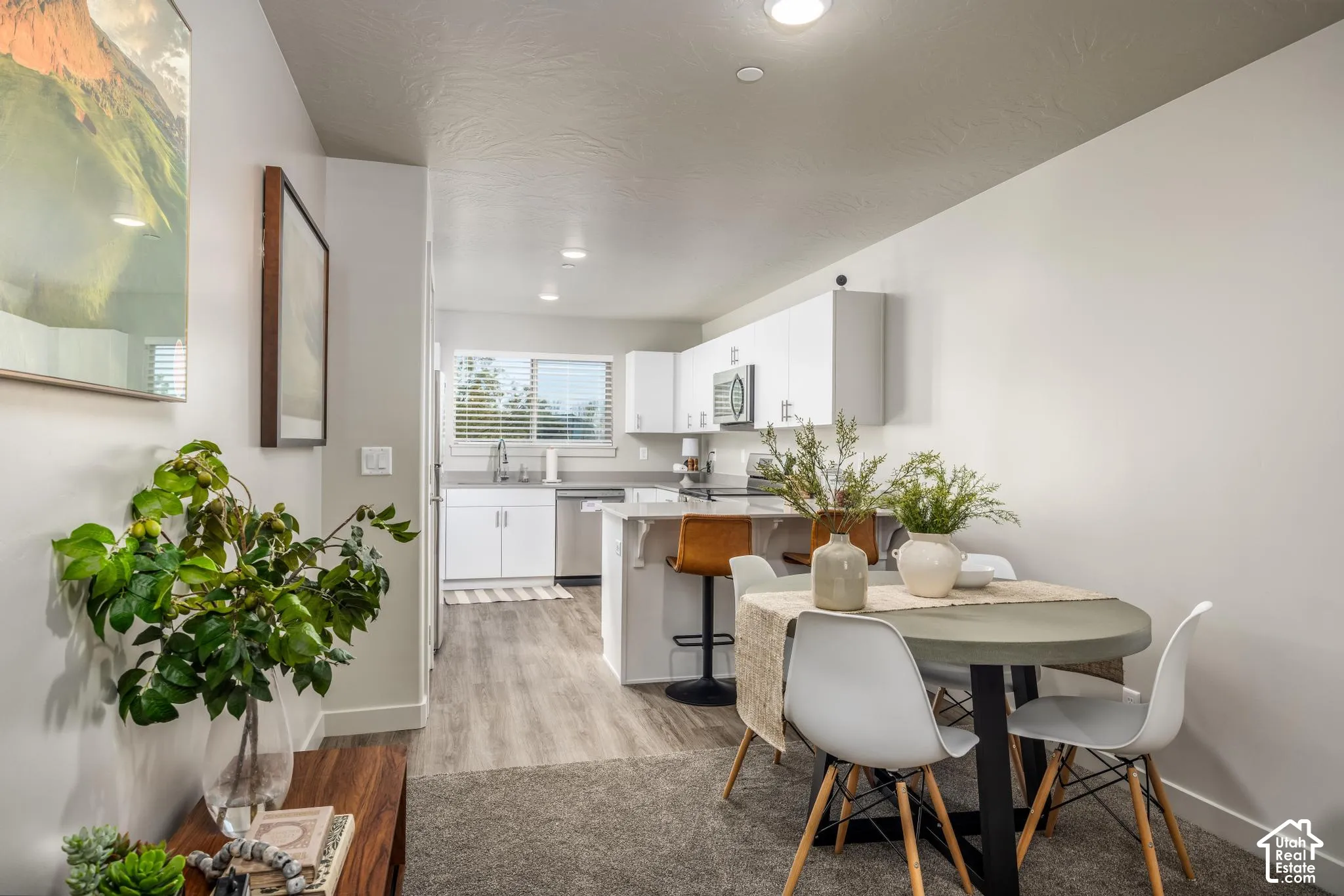 Kitchen featuring white cabinetry, stainless steel appliances, neutral stone-finish countertops, wood-finish flooring, and recessed lighting