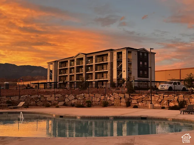 Multi-story building featuring stone veneer siding, private balconies, an inground pool with concrete surround, and mountain scenery