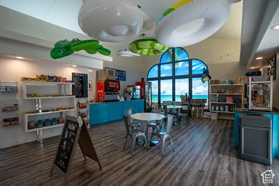 Vaulted ceilings with recessed lighting, wood-finish flooring, built-in shelving, blue cabinetry, and a large arched window with a scenic backdrop