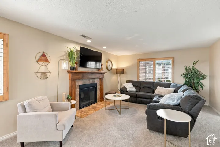 Fireplace featuring a stone tile surround and a wood mantel, flanked by windows with wood-finish plantation shutters and recessed lighting