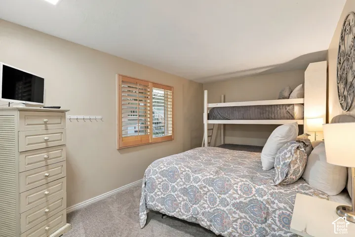 Room featuring neutral wall tones, wall-to-wall carpeting, and a window fitted with wood-finish plantation shutters