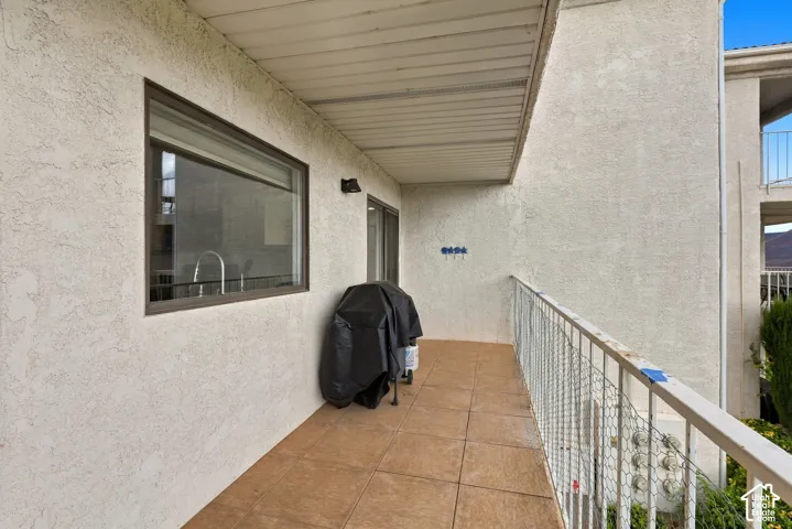 Covered balcony featuring a stucco exterior, tile flooring, and a metal railing