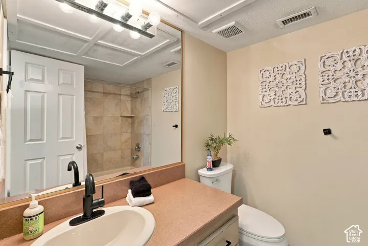 Bathroom featuring a vanity with a solid-surface countertop, an integrated oval basin, a matte black faucet, and a tiled shower enclosure