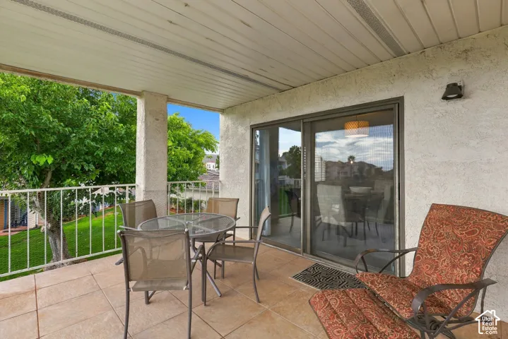 Covered patio featuring ceramic tile flooring, a white metal railing, and sliding glass door access