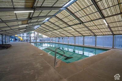 Enclosed swimming pool with a translucent vaulted ceiling, integrated lighting, and glass panel walls