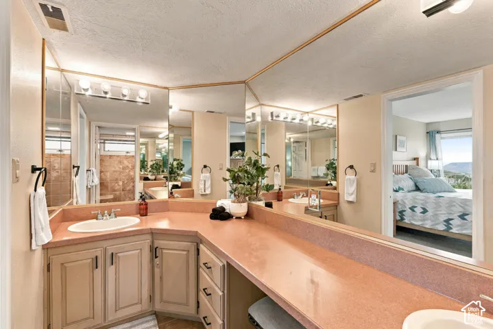 Extended vanity featuring solid-surface countertops, integrated oval sinks, multi-section wall-to-wall mirror, and painted cabinetry with storage drawers