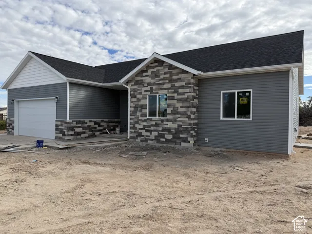 Exterior facade featuring gray horizontal siding, multi-tonal masonry accents, a pitched roofline, and an attached two-car garage