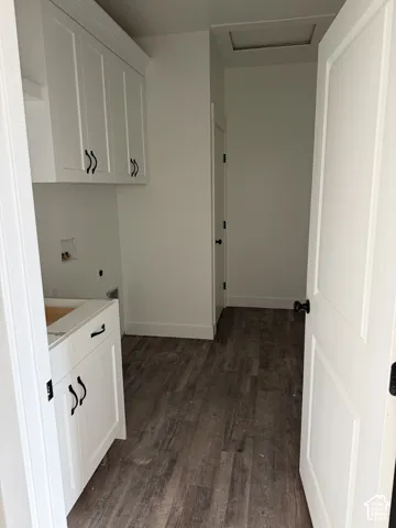 Utility room featuring white shaker-style cabinetry, wood-finish flooring, and matte black hardware