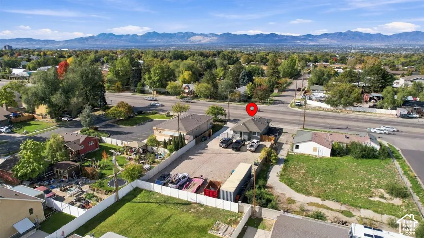 Aerial perspective featuring mountain range backdrop, expansive gravel parking area, and vinyl privacy fencing