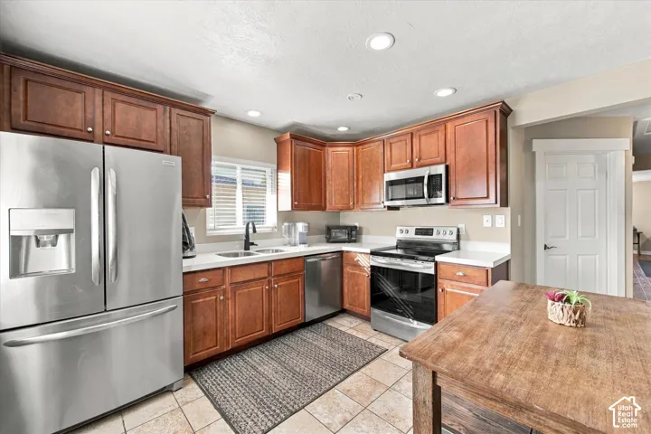 Kitchen featuring wood cabinetry, stainless steel appliances, white quartz countertops, dual-basin undermount sink, and recessed lighting