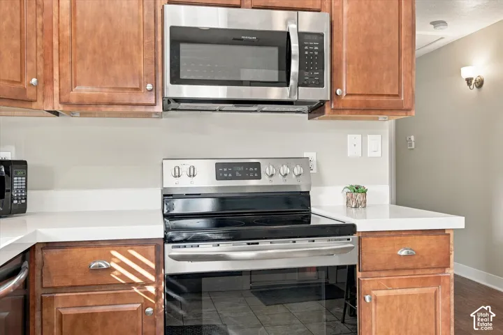 Kitchen area featuring wood cabinetry, stainless steel microwave, stainless steel range, and white quartz countertops