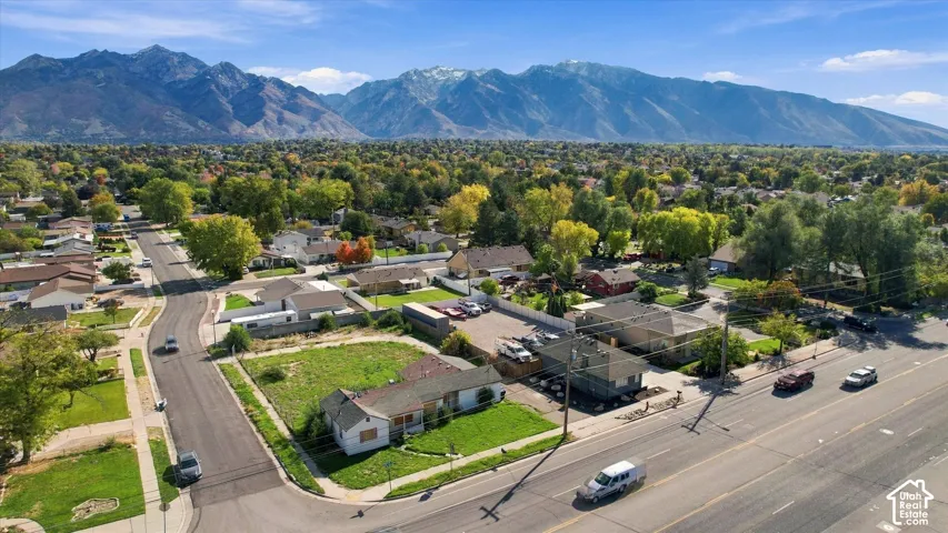 Aerial perspective showcasing a residential property with a grass lawn, paved driveway, and prominent mountain backdrop