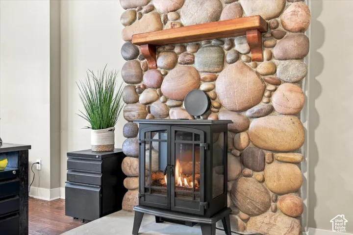Floor-to-ceiling river rock hearth featuring a freestanding black metal fireplace and a natural wood-finish mantel
