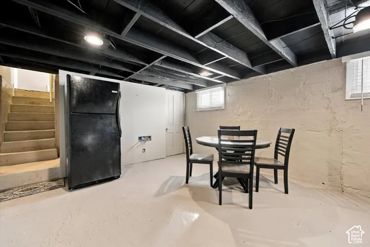 Finished concrete flooring, exposed ceiling joists with black finish, painted masonry walls, and inset window with white trim
