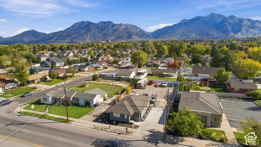 Aerial perspective featuring mountain backdrops, paved parking areas, multi-structure site layout, and mature perimeter trees