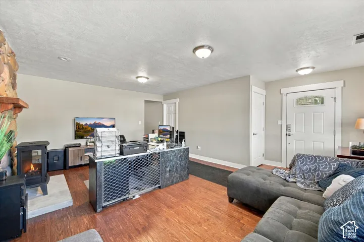 Living area featuring wood-finish flooring, a stone-accented fireplace surround, a cast-iron stove, and a door with an arched glass insert