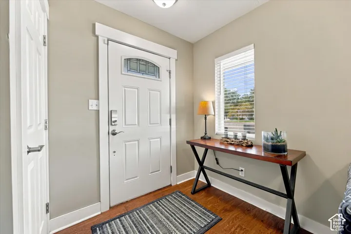 Entry area featuring wood-finish flooring, a six-panel door with a glass transom, and a single-hung window with blinds