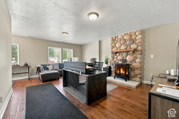 Wood-finish flooring, river stone fireplace surround, wood mantel, and flush-mount ceiling lighting