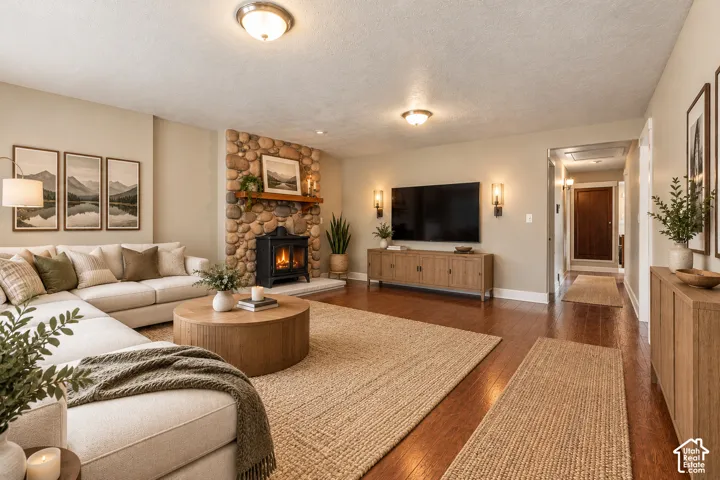 Living area featuring river rock fireplace surround, wood-finish flooring, ceiling-mounted light fixtures, and wall sconces