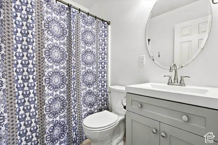Bathroom featuring a vanity with shaker-style cabinetry, a white countertop with an integrated basin, a polished chrome dual-handle faucet, and a frameless oval wall mirror