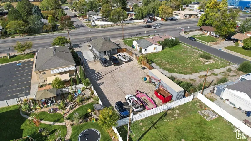 Aerial view of property featuring a gravel parking area, detached storage structure, concrete driveway, and perimeter fencing