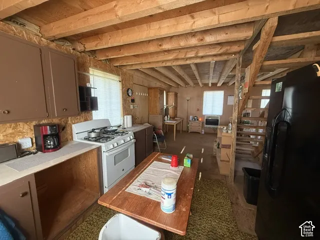 Kitchen featuring solid wood cabinetry, gas range, exposed timber ceiling joists, and integrated wood staircase