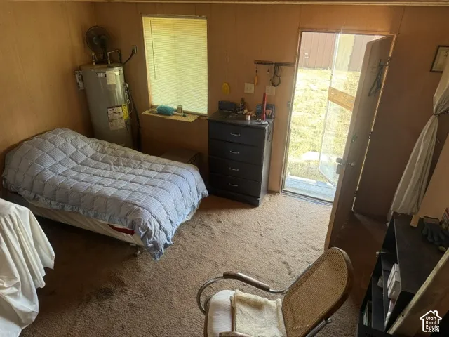 Room featuring wood-paneled walls, carpeted flooring, a recessed window with blinds, and an exterior door