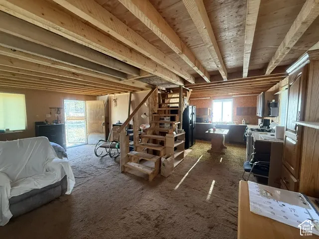 Exposed wood ceiling beams, wood-construction open staircase with integrated shelving, and cabinetry