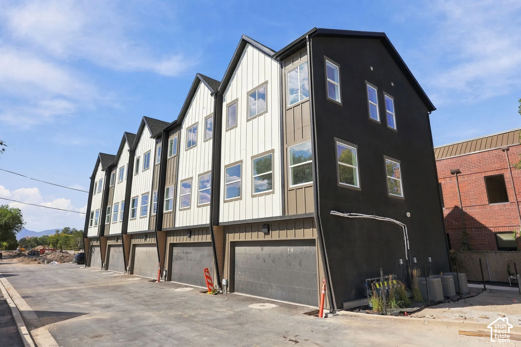 Modern multi-level townhome featuring a striking dark exterior with contrasting light vertical siding and multiple windows
