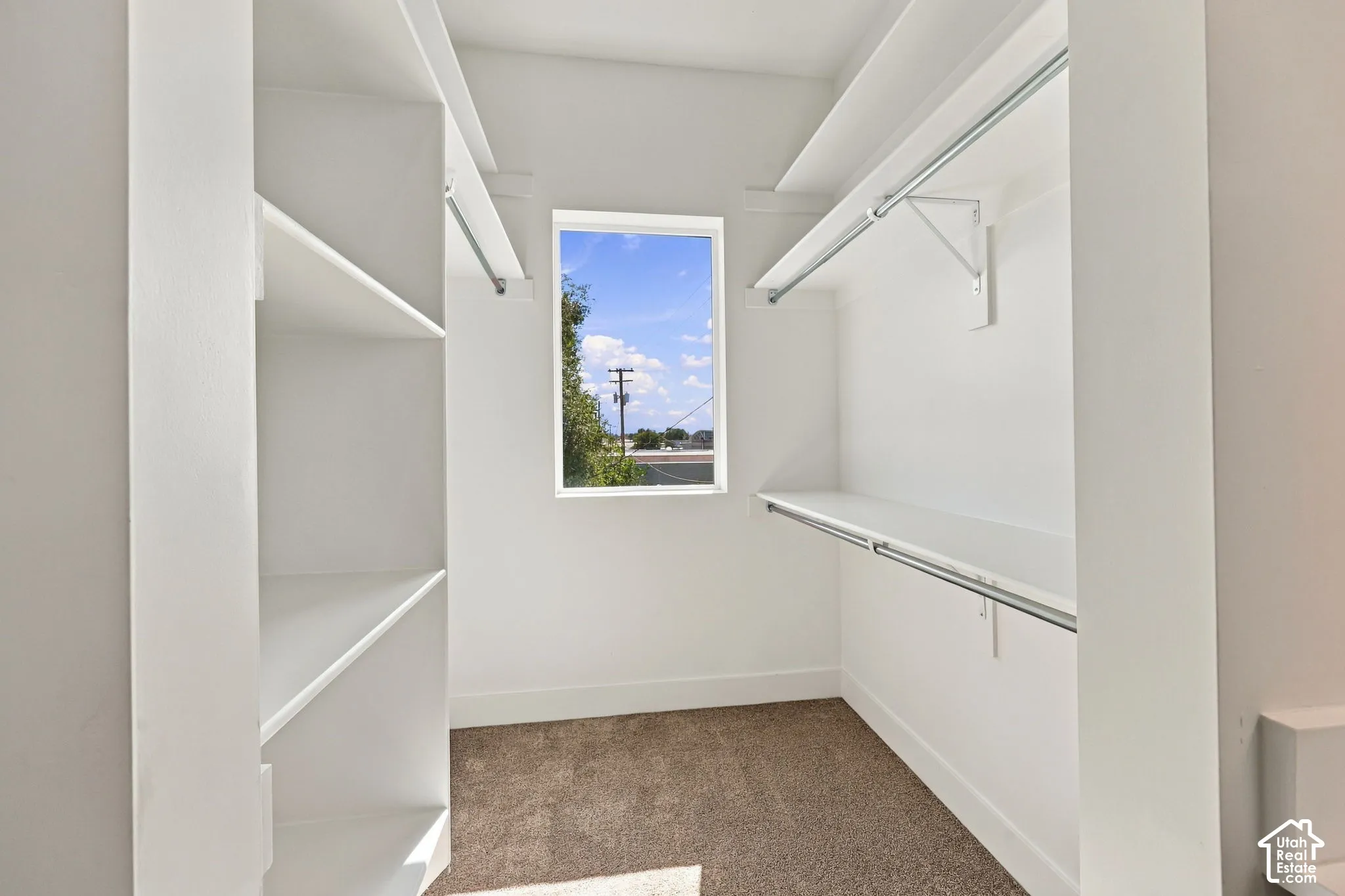 Walk-in closet with built-in shelving, hanging rods, and a window