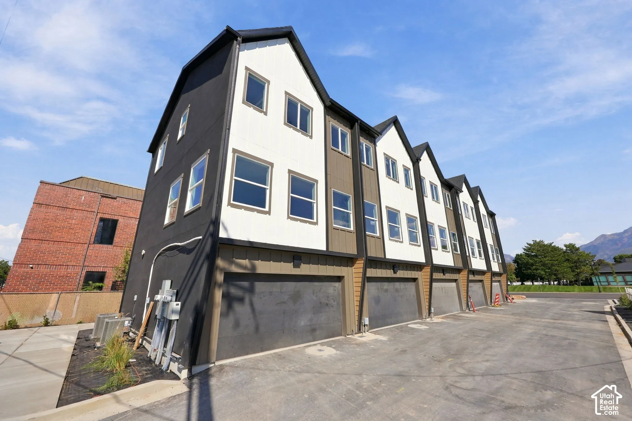 Modern multi-unit residence featuring steeply pitched gable rooflines with contrasting dark and cream exterior finishes, large multi-pane windows providing abundant natural light, and ground-level garage parking with dark facade detailing
