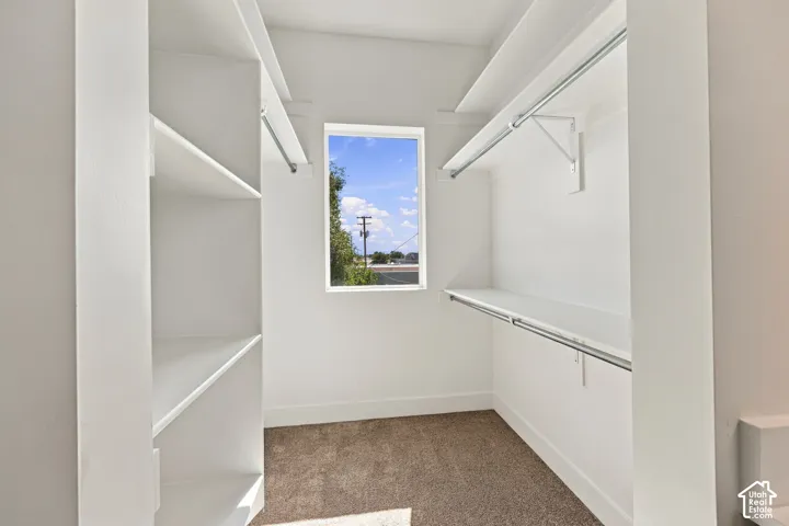 Walk-in closet with built-in shelving, hanging rods, and a window