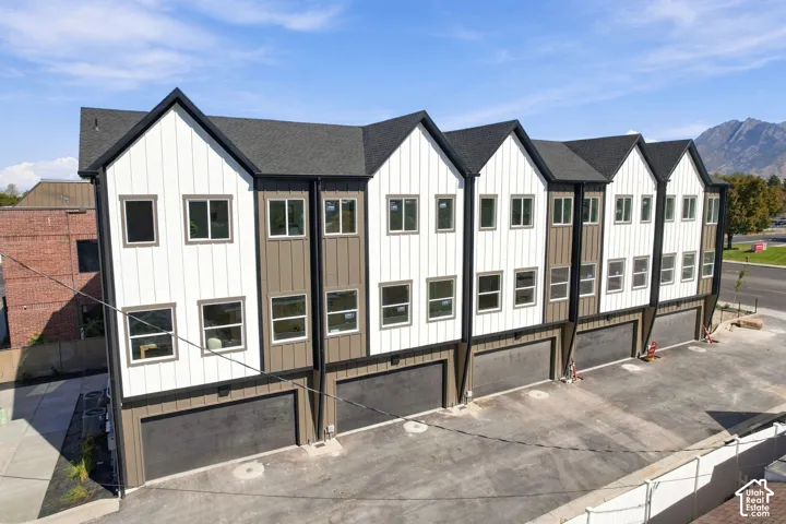 Modern townhome architecture featuring vertical siding, gabled rooflines, multiple windows, and individual garage access
