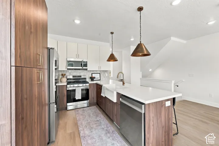 Gourmet kitchen with stainless steel appliances, wood-finish cabinetry, white countertops, and a tile backsplash
