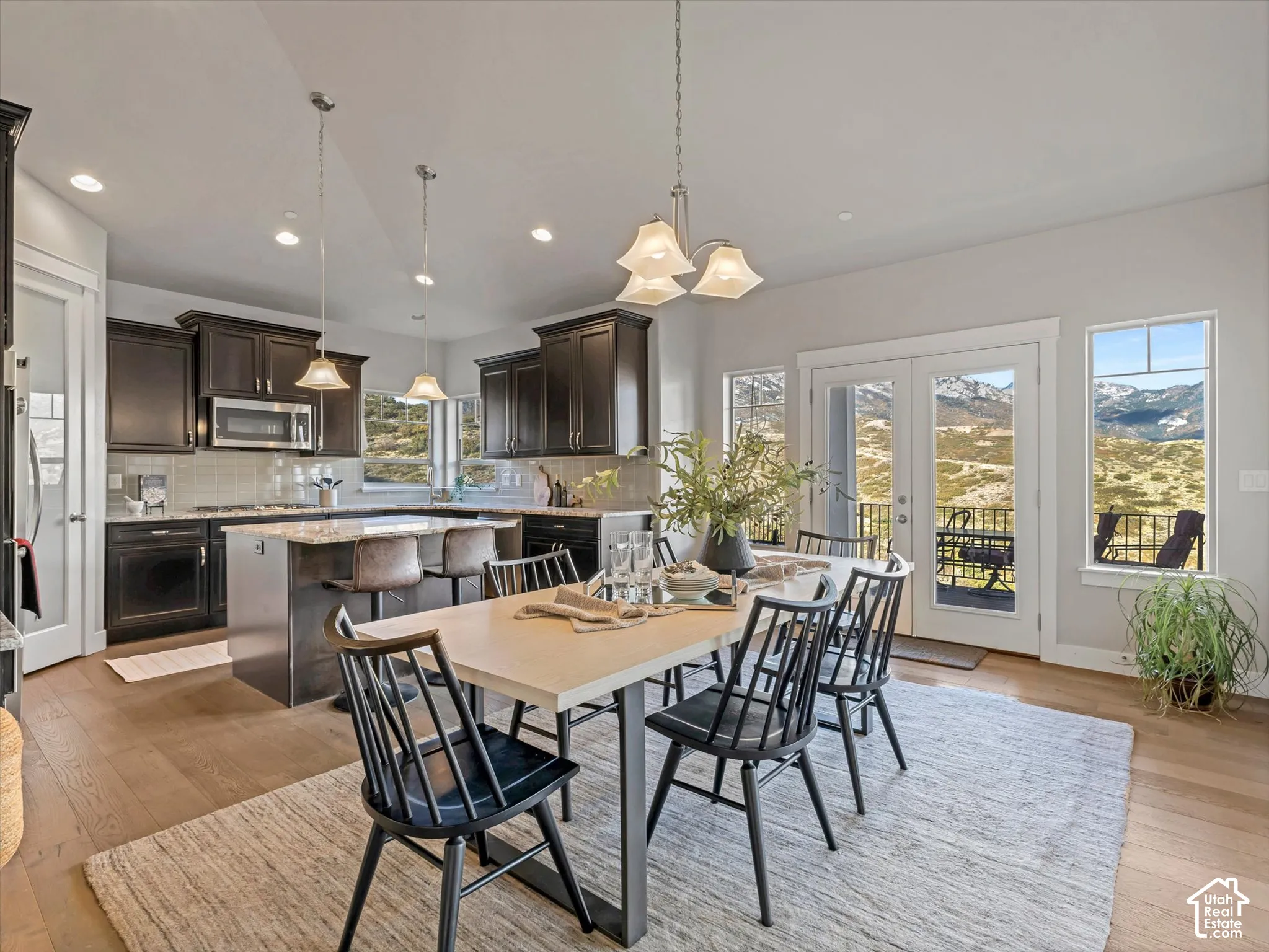 Kitchen featuring stained wood cabinetry, stone countertops, a central island, wood-finish flooring, and dual glass-paned doors with mountain scenery
