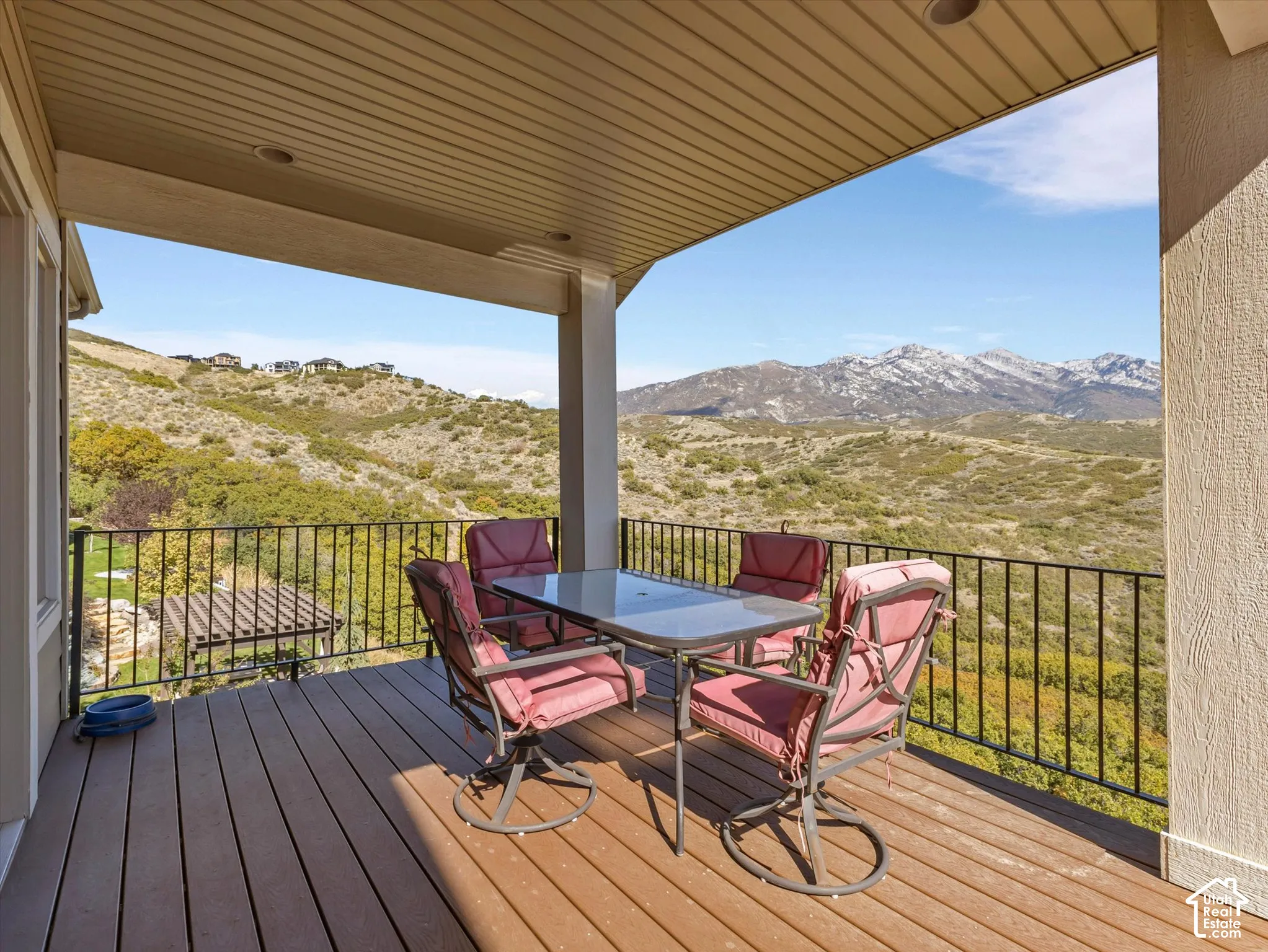 Covered outdoor deck with composite wood-finish decking, black metal railing, recessed ceiling lighting, and mountain scenery