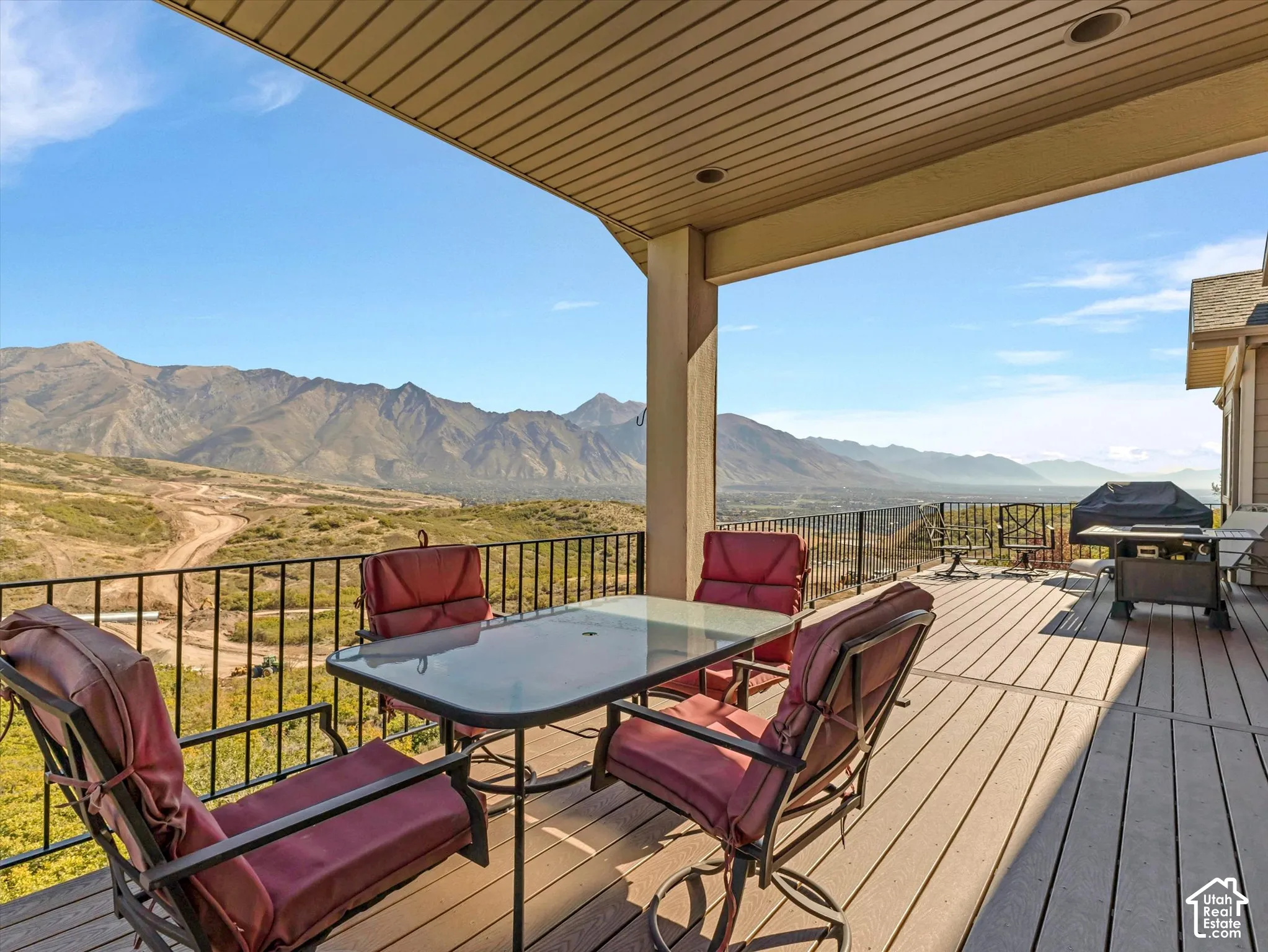 Covered deck featuring composite decking, black metal railing, and mountain backdrop