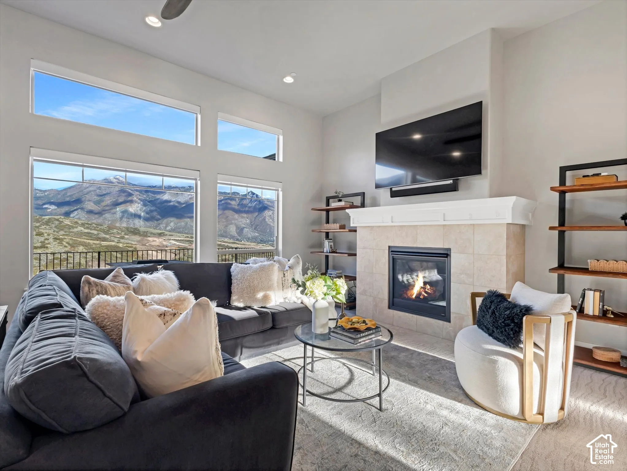 Living room featuring high ceilings, large windows with mountain scenery, a gas fireplace with a tiled surround, and integrated recessed lighting