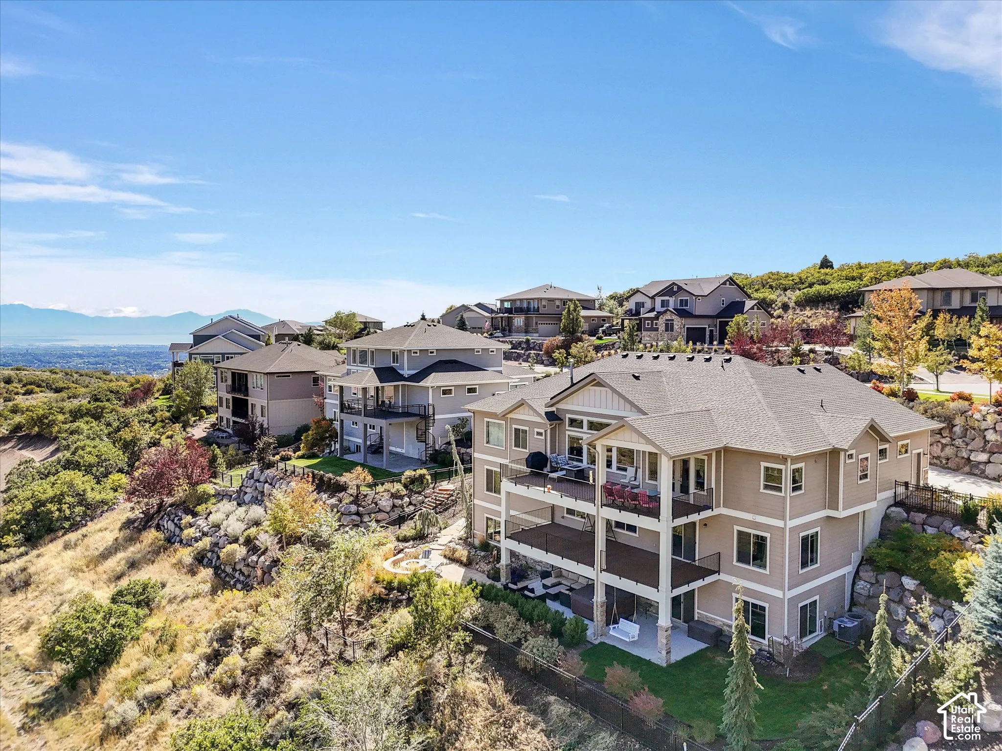 Multi-level exterior featuring wood-composite siding, two-tiered covered decks with railings, stone foundation accents, and a walk-out patio area