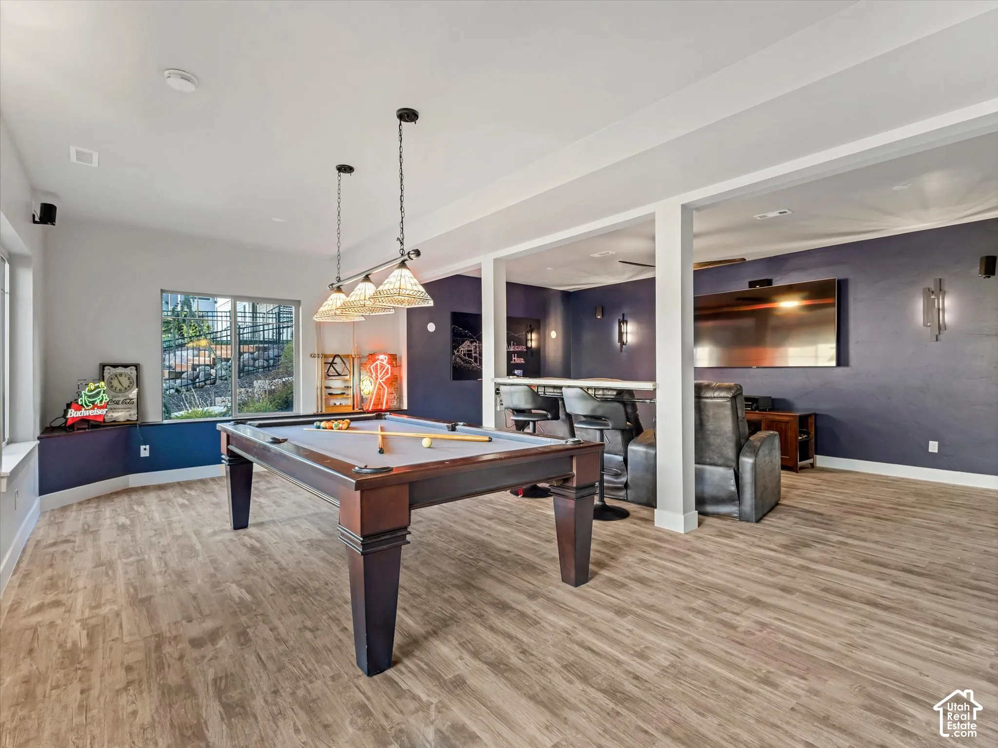 Open-concept interior featuring wood-finish flooring, accent walls, recessed lighting, and a multi-pendant light fixture