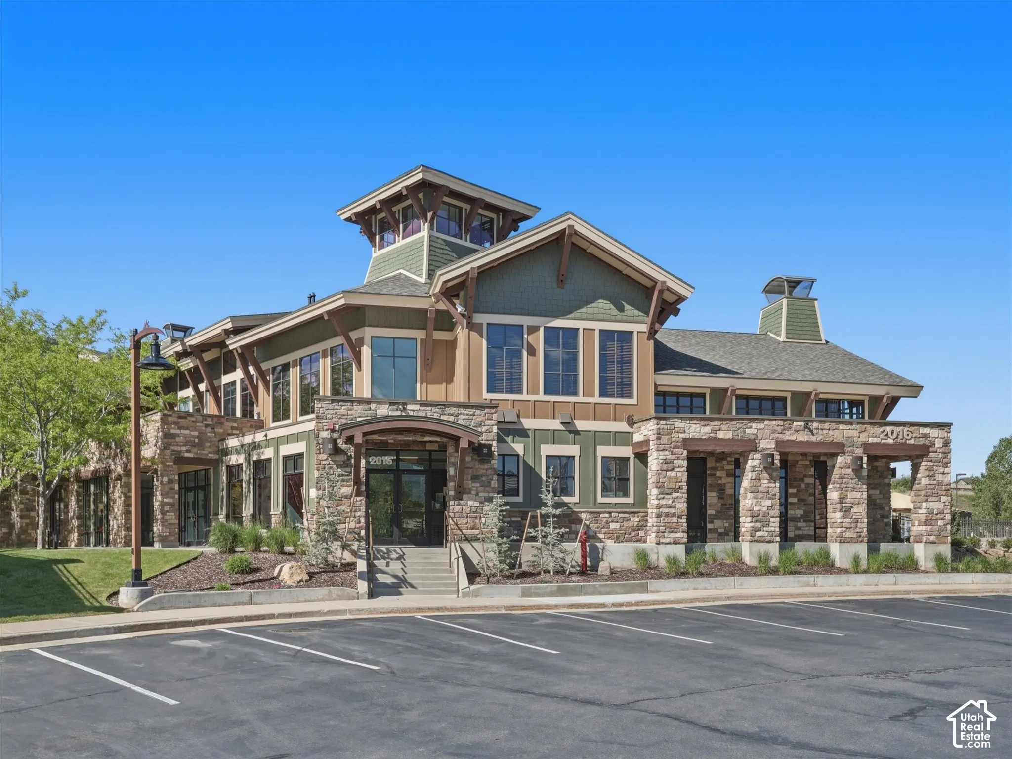 Exterior featuring multi-textured siding, stone masonry detailing, prominent wood-beam accents, a central cupola, and covered entry portico