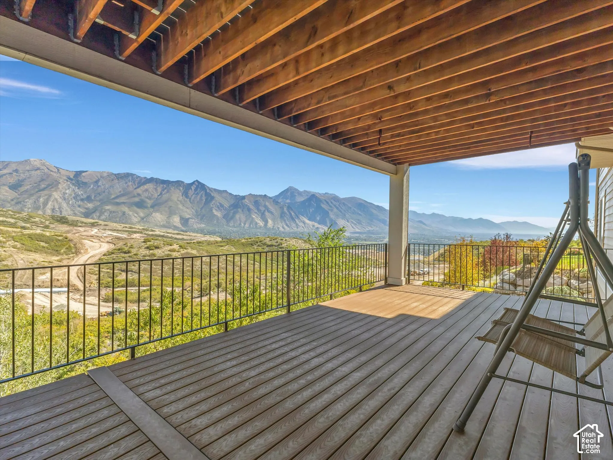 Covered deck with composite decking, exposed timber joist ceiling, and metal railing overlooking mountain scenery