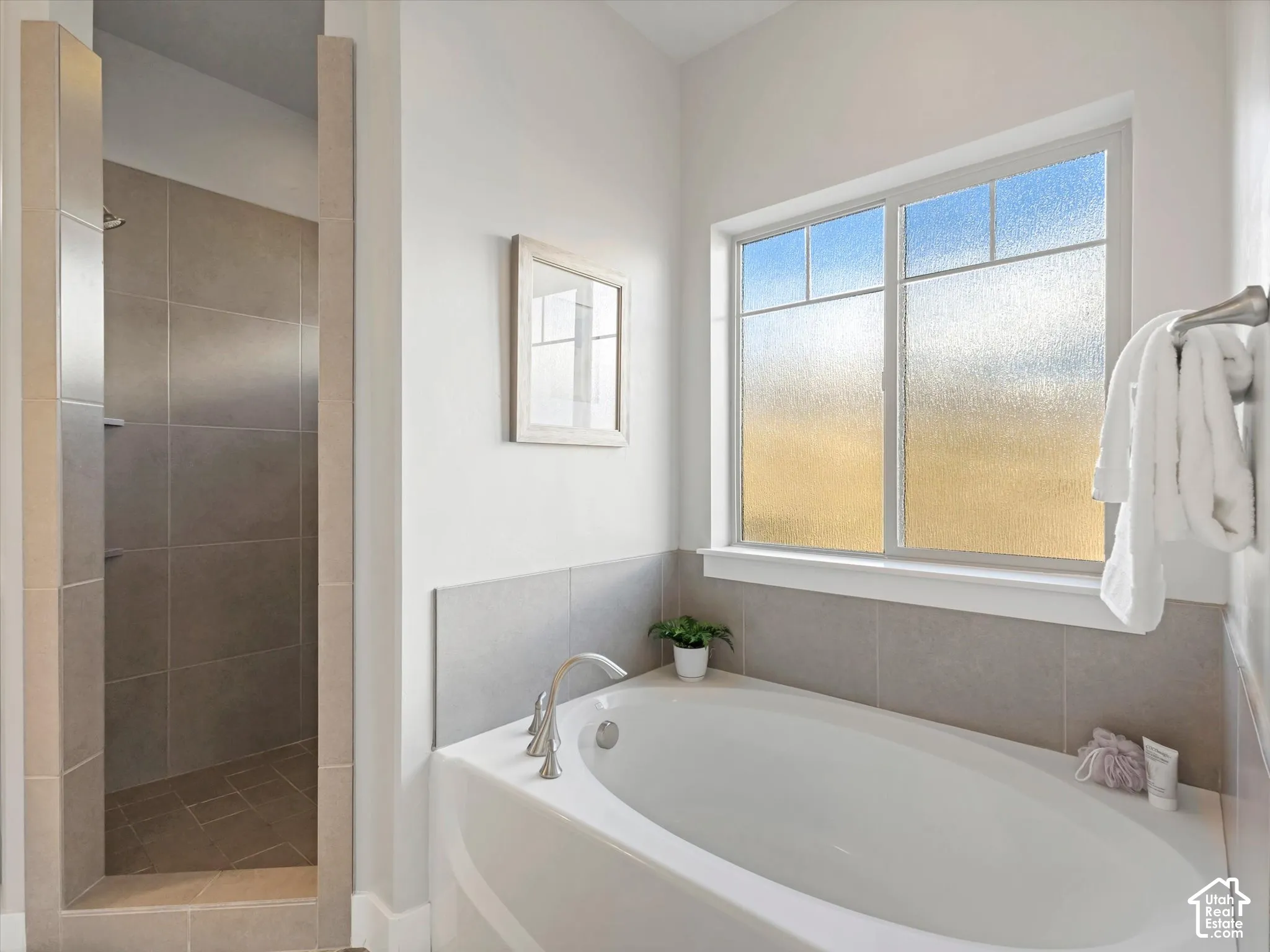 Bathroom featuring an oval soaking tub with deck-mounted faucet, walk-in tiled shower, and privacy-glass window