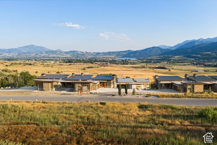 Exterior architecture featuring stone masonry siding, metal roofing, expansive paved driveways, and mountain scenery