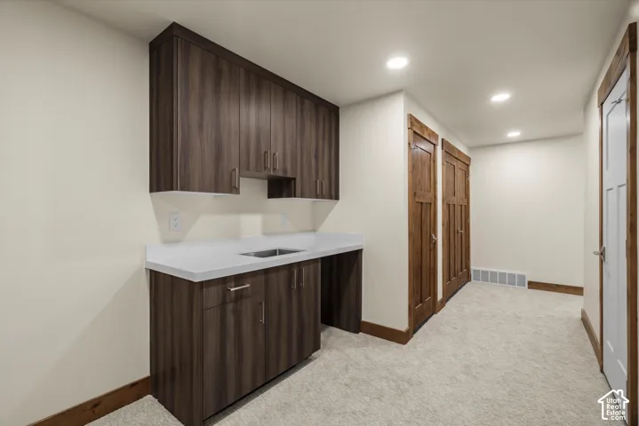 Built-in cabinetry with dark wood-finish cabinetry, solid surface countertop, integrated sink, and recessed lighting